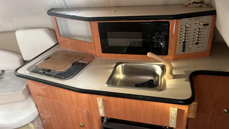 Slide: The Image of 2000 Regal Commodore 2460 boat interior with kitchenette, sink, stove, and microwave. - 9