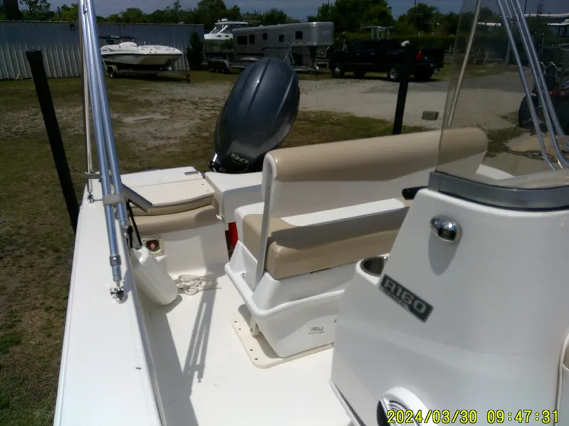 Slide: The Image of 2018 Robalo R160 cc boat with beige seating, parked outdoors. - 10