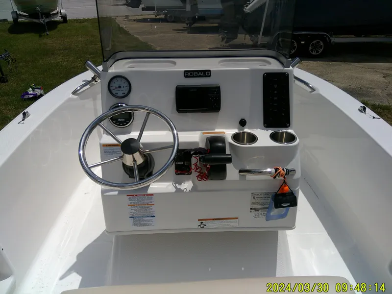 Slide: The Image of 2018 Robalo R160 cc boat console with steering wheel, gauges, and cup holders. - 12