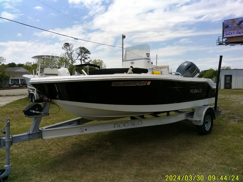 Slide: The Image of 2018 Robalo R160 cc boat on trailer, parked on grass under a partly cloudy sky. - 3