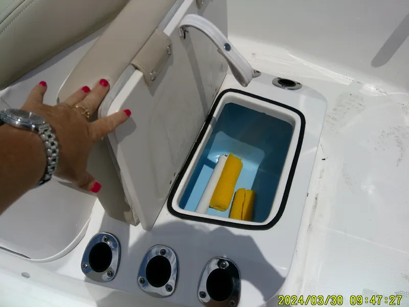 Slide: The Image of 2018 Robalo R160 cc boat seat storage compartment with cleaning supplies. - 9