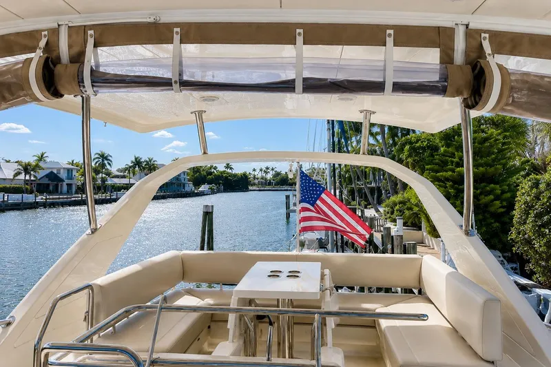 Slide: The Image of Aquila 44 Yacht 2016 with American flag, docked by palm-lined waterfront homes. - 7