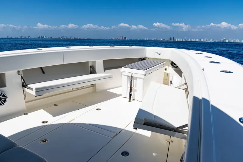 Slide: The Image of 2019 SeaVee 390Z boat deck with seating, ocean view, and city skyline in the background. - 15