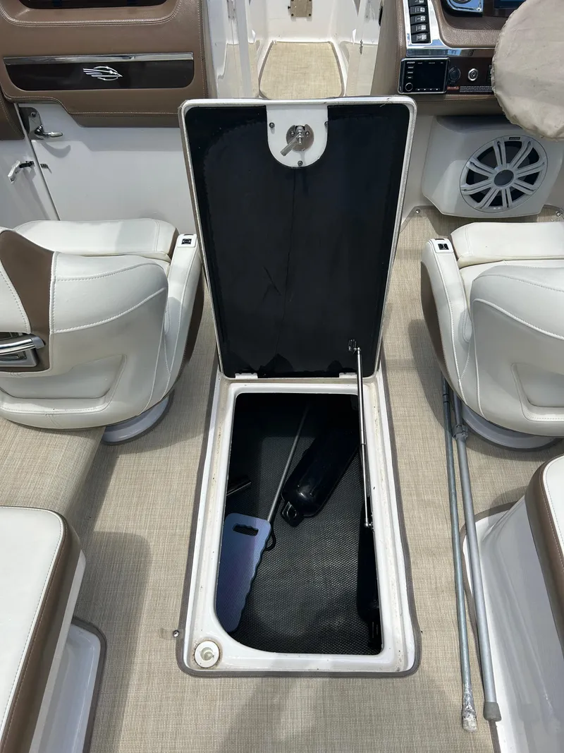 Slide: The Image of 2016 Chaparral 257 SSX boat interior with open storage compartment, white seating, and beige flooring. - 22
