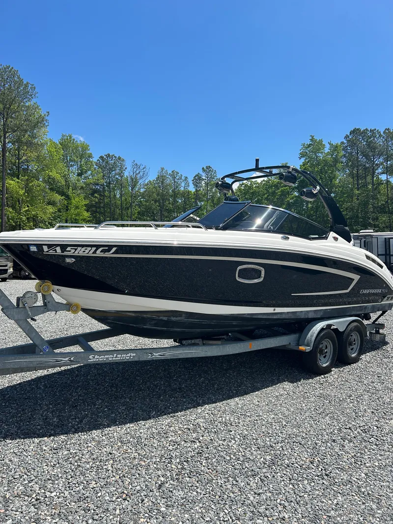 Slide: The Image of 2016 Chaparral 257 SSX boat on trailer, parked outdoors on gravel, surrounded by trees. - 7