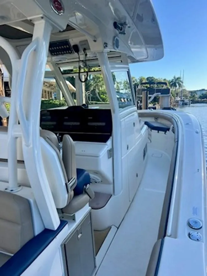 Slide: The Image of 2017 Scout LXF 350 boat interior with seating and control panel, docked by a scenic waterfront. - 4