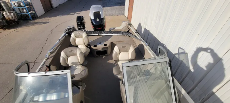 Slide: The Image of 2004 Sylvan F 1800 AVENGER boat with beige seating and outboard motor, parked outdoors. - 17