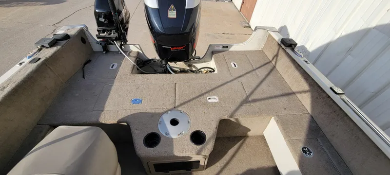 Slide: The Image of 2004 Sylvan F 1800 Avenger boat interior with motor, beige carpet, and seating area. - 21