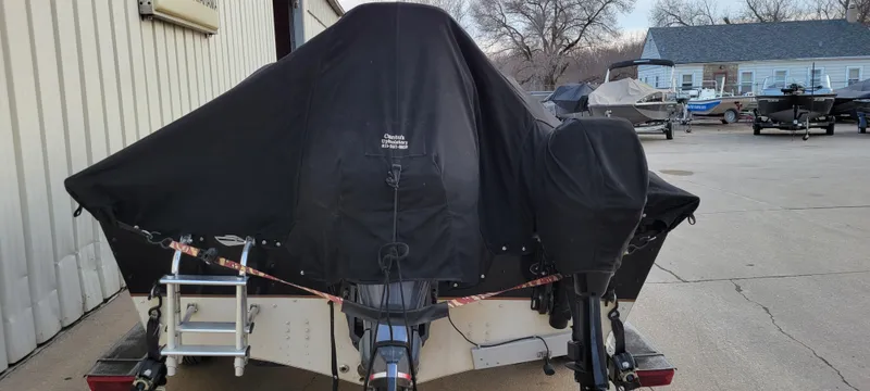 Slide: The Image of 2004 Sylvan F 1800 Avenger boat covered, parked outdoors near other boats. - 25