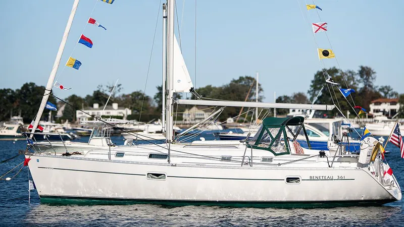 Slide: The Image of Sailboat Beneteau 361, 1999 model, adorned with colorful flags on a calm waterway. - 0