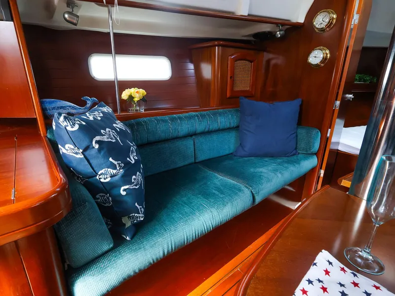 Slide: The Image of Interior of 1999 Beneteau 361 yacht with teal seating, decorative pillows, and wooden accents. - 21