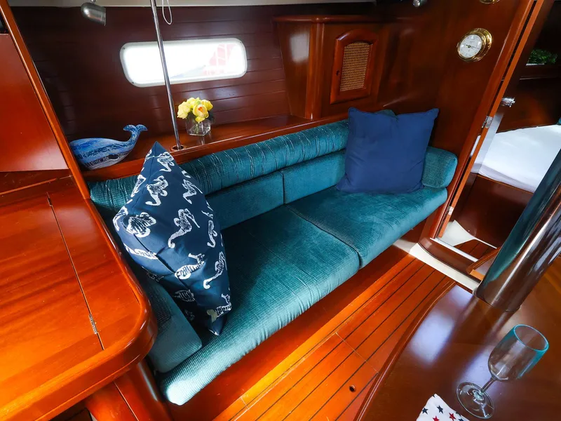 Slide: The Image of Interior of 1999 Beneteau 361 sailboat with teal sofa, wooden finish, and decorative pillows. - 22