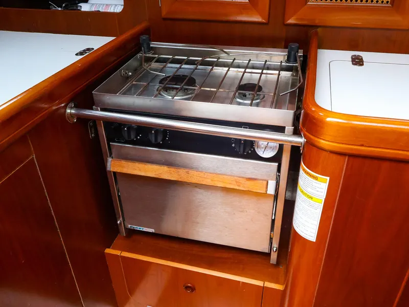 Slide: The Image of 1999 Beneteau 361 yacht kitchen with stainless steel stove and wooden cabinetry. - 27
