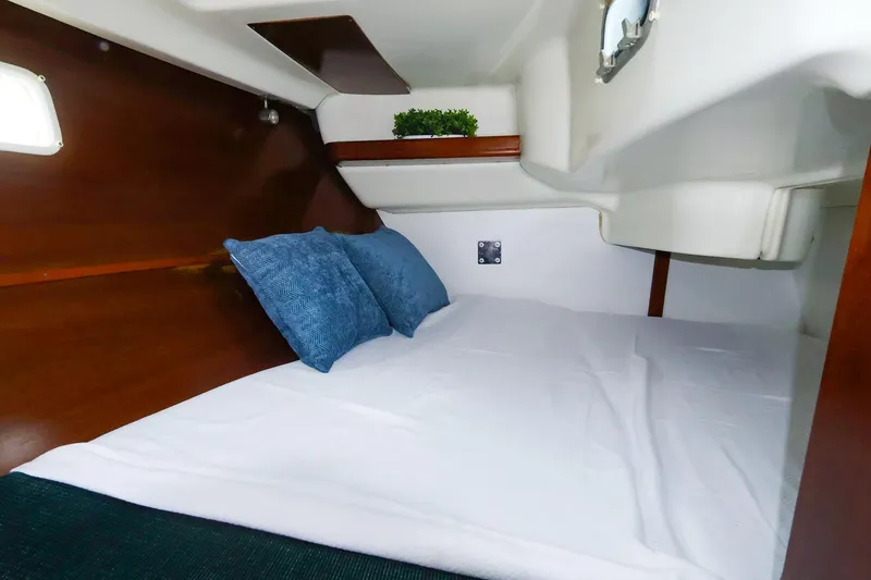 Slide: The Image of Cozy cabin interior of 1999 Beneteau 361 sailboat with blue pillows and wooden accents. - 43