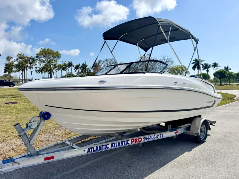Slide: The Image of 2021 Bayliner VR5 OB boat on trailer with canopy, parked outdoors under blue sky. - 1