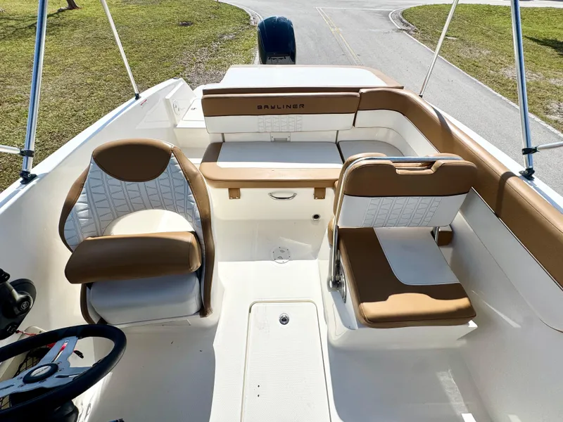 Slide: The Image of 2021 Bayliner VR5 OB boat interior with tan and white seating, steering wheel, and open deck. - 10