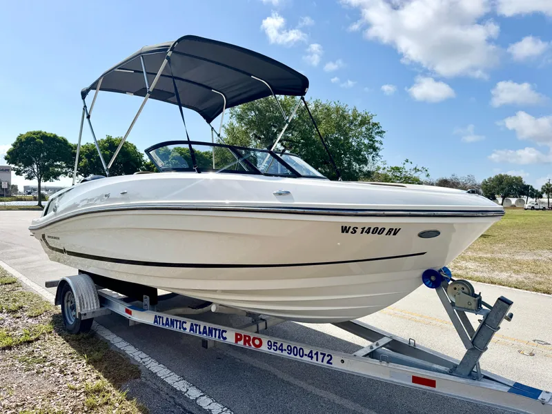 Slide: The Image of 2021 Bayliner VR5 OB boat on trailer with canopy, parked outdoors under blue sky. - 5