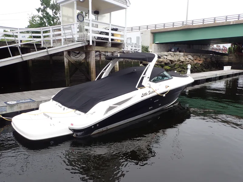 Slide: The Image of 2010 Sea Ray 300 SLX boat docked near a bridge, covered with a black tarp. - 5