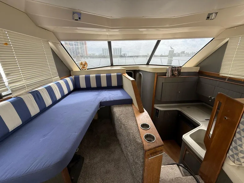 Slide: The Image of Interior of a 1995 Catalina Islander 34 boat with striped seating and compact kitchen area. - 11