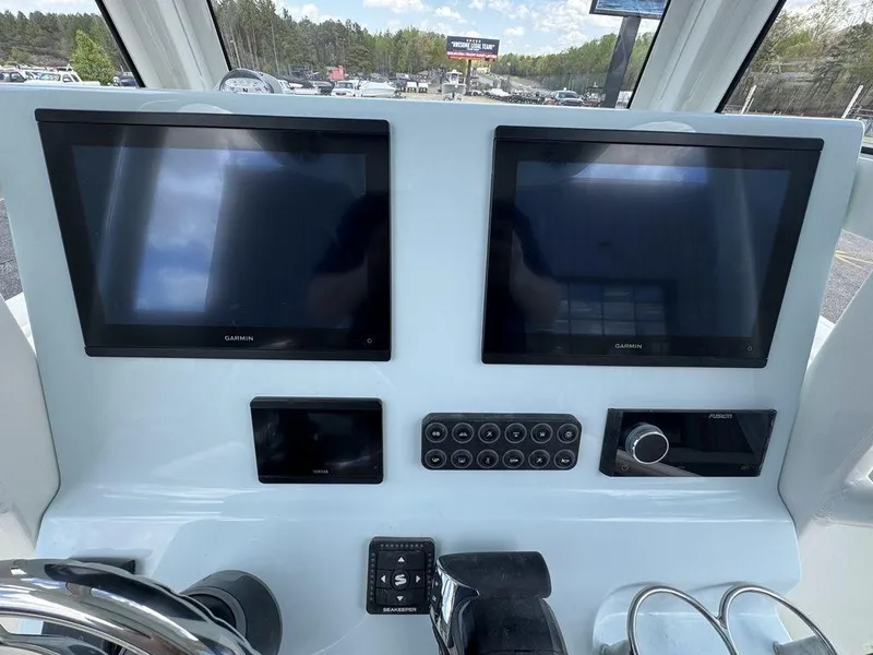 Slide: The Image of 2025 Key West 239 FSR boat interior with speaker, overlooking a marina with multiple boats. - 14