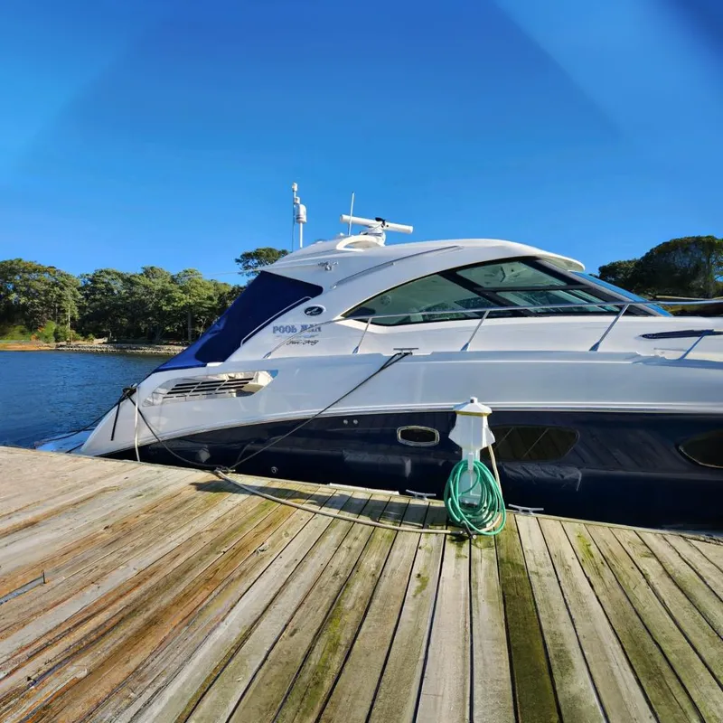 Slide: The Image of 2011 Sea Ray 540 Sundancer yacht docked by a wooden pier, with clear blue sky. - 2