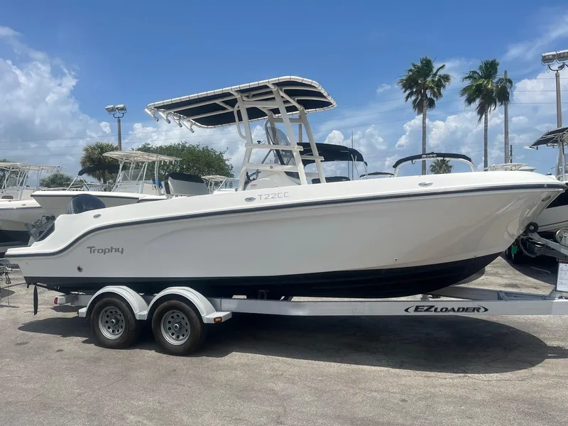 The Image of 2022 Bayliner Trophy T22CC boat on trailer, parked outdoors under a blue sky. - 0