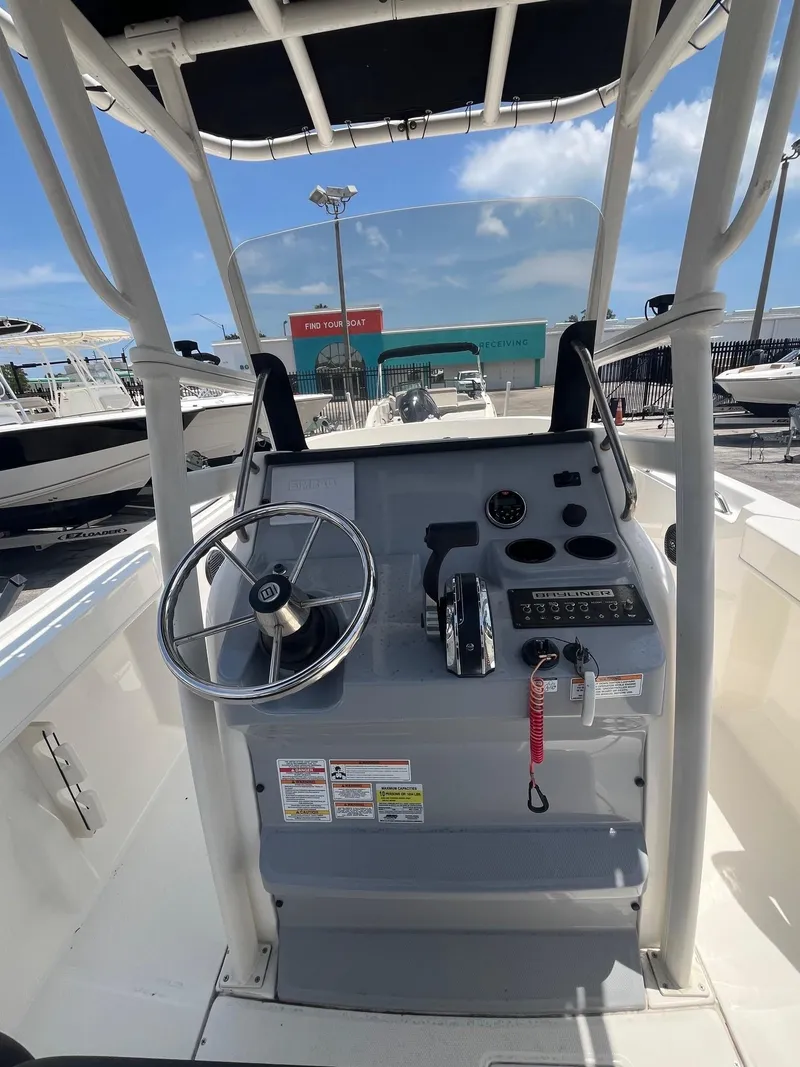 Slide: The Image of 2022 Bayliner Trophy T22CC boat console with steering wheel and controls, docked under clear sky. - 5