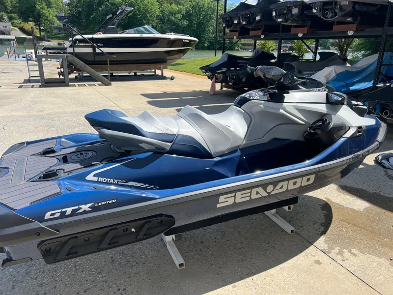 Slide: The Image of 2023 Sea-Doo GTX 300 jet ski in blue, parked on a sunny dock. - 2