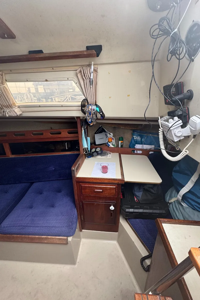 Slide: The Image of Interior of a 1985 O'Day Sloop sailboat with blue seating and wooden cabinetry. - 10