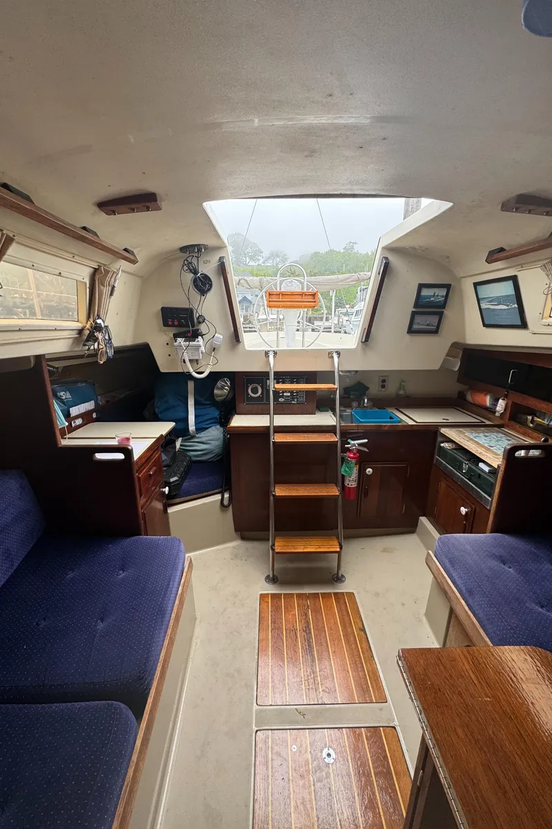 Slide: The Image of Interior of a 1985 O'Day Sloop sailboat with wooden accents and seating. - 12