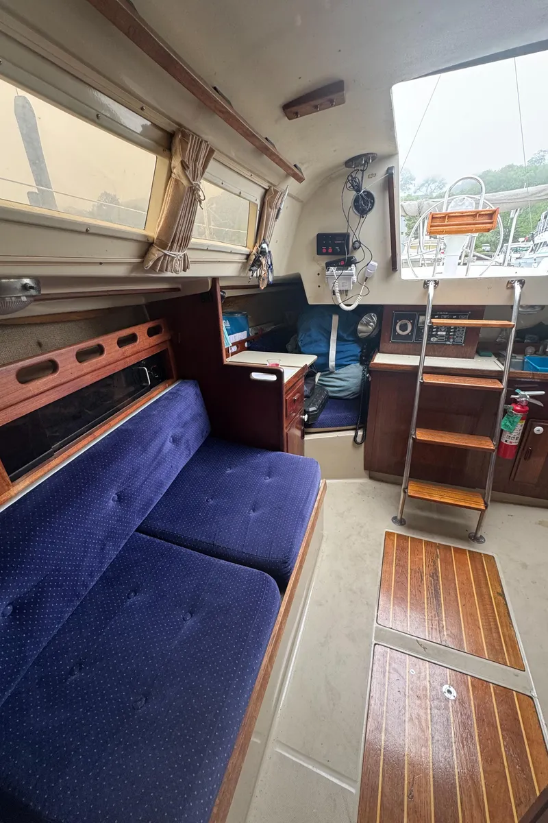 Slide: The Image of Interior of a 1985 O'Day Sloop sailboat with blue seating and wooden accents. - 13