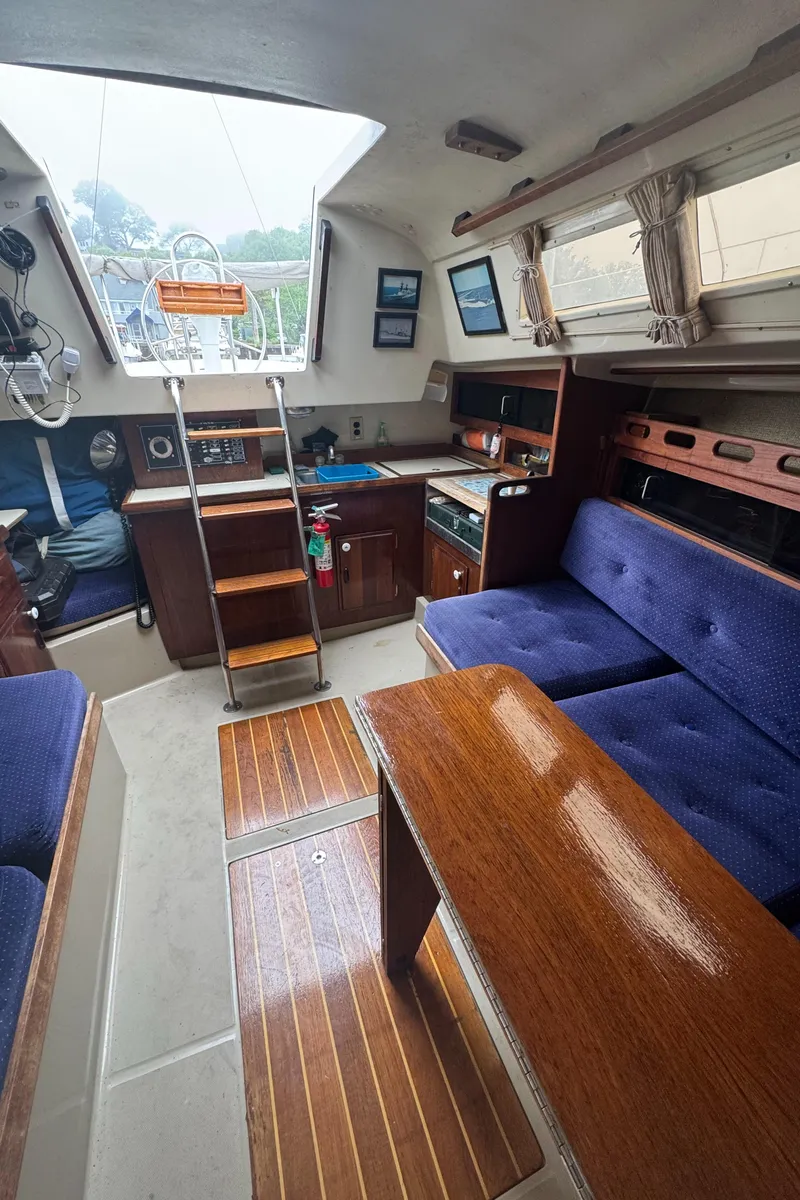 Slide: The Image of Interior of a 1985 O'Day Sloop sailboat with cozy seating and wooden accents. - 14