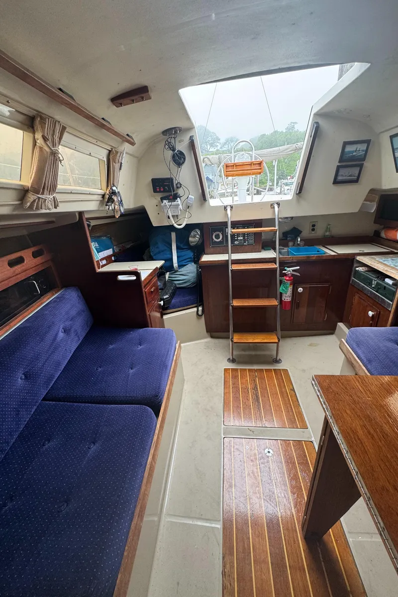 Slide: The Image of Interior of a 1985 O'Day Sloop sailboat with blue seating and wooden accents. - 15
