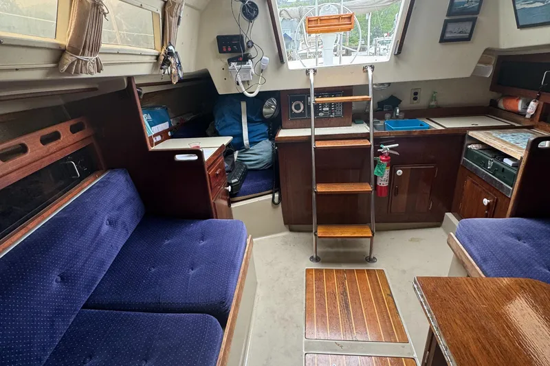 Slide: The Image of 1985 O'Day Sloop interior with blue seating, wooden accents, and navigation equipment. - 16
