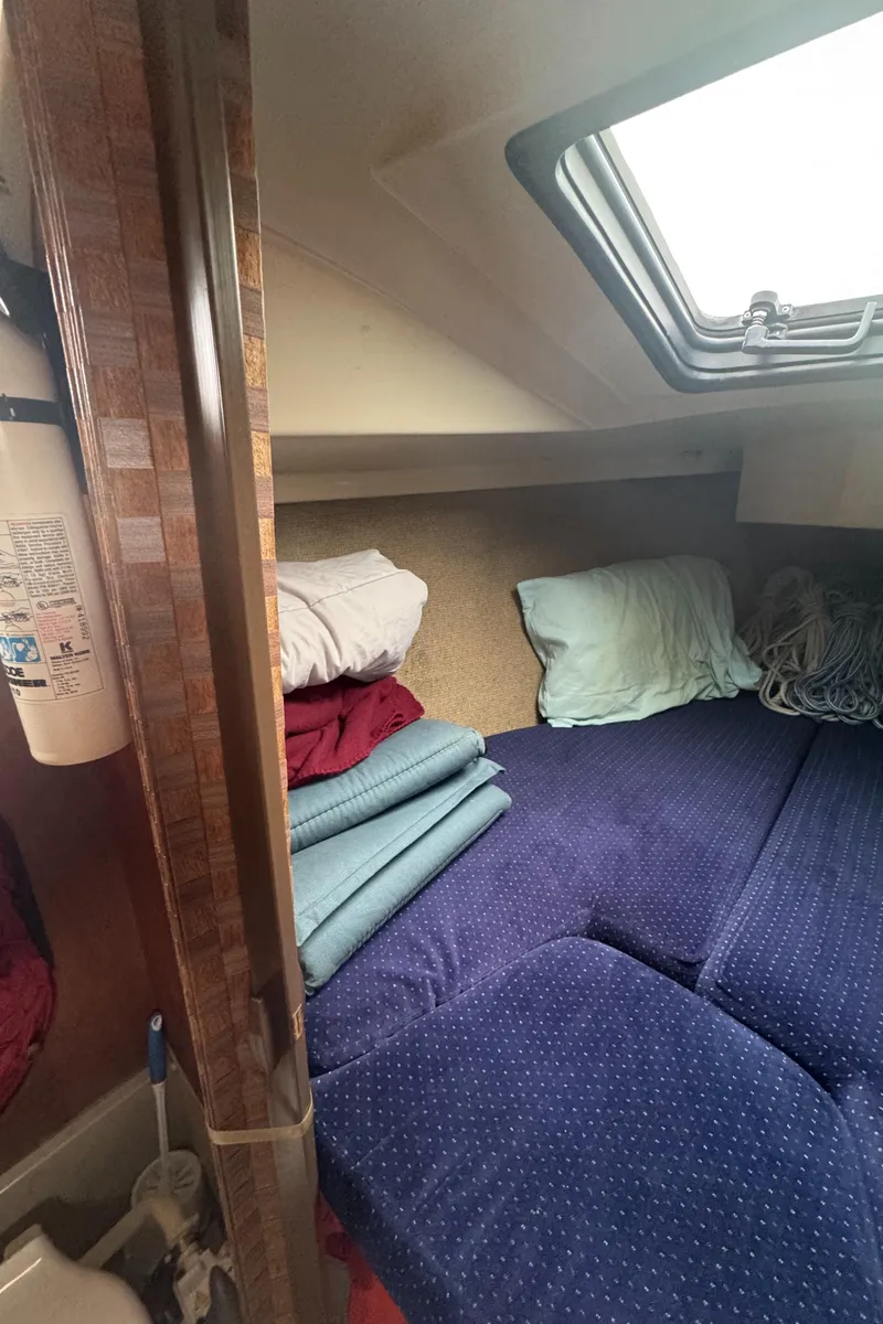 Slide: The Image of 1985 O'Day Sloop cabin interior with blue bedding and a small window. - 20