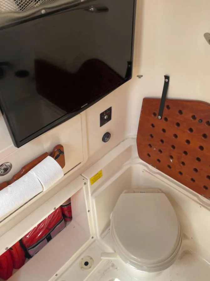 Slide: The Image of 2015 Grady-White 336 Canyon boat interior with toilet and mounted TV. - 13