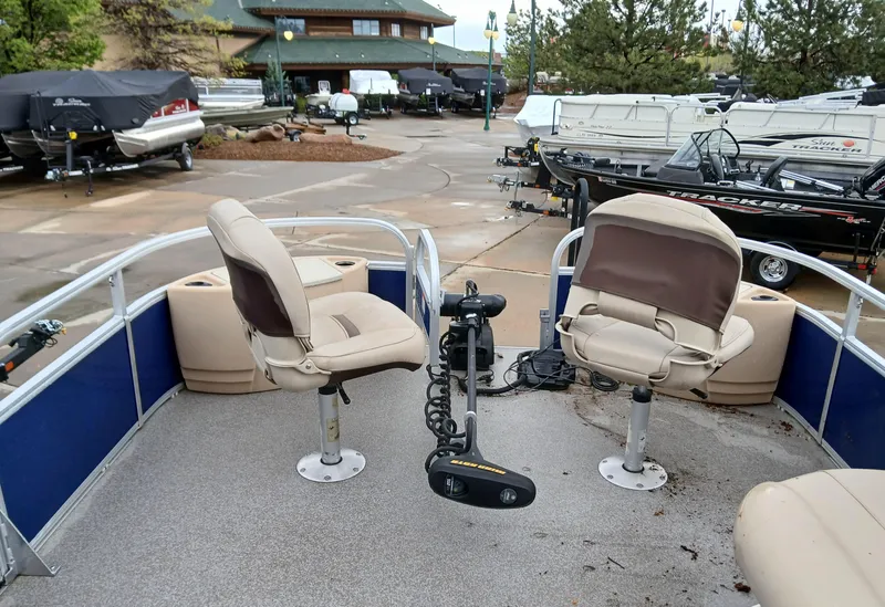 Slide: The Image of 2017 Sun Tracker FB 24XP3 pontoon boat with swivel seats and trolling motor in a marina. - 2