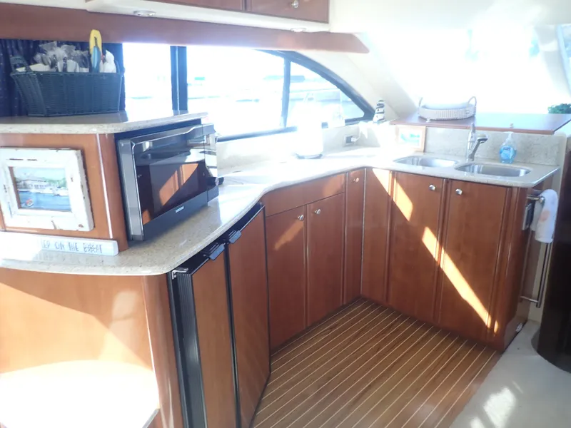 Slide: The Image of 2006 Meridian 411 Sedan yacht kitchen with wood cabinets, microwave, and sink. - 14