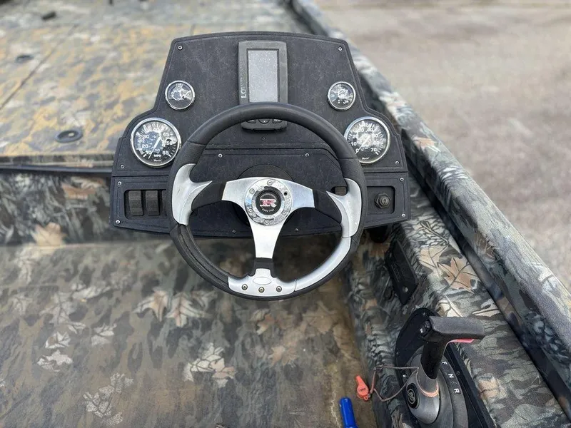Slide: The Image of 2015 Ranger RC188 boat dashboard with steering wheel and gauges, featuring a camouflage design. - 2