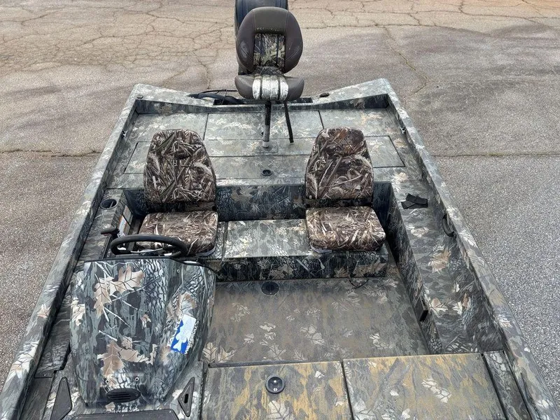 Slide: The Image of 2015 Ranger RC188 boat with camouflage seats and steering, parked on pavement. - 5