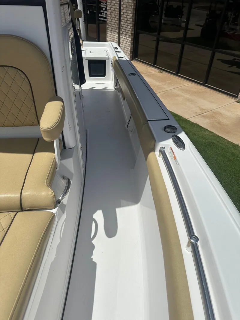 Slide: The Image of 2023 Sportsman Masters 247OE Bay Boat interior with tan seating and sleek white deck. - 10
