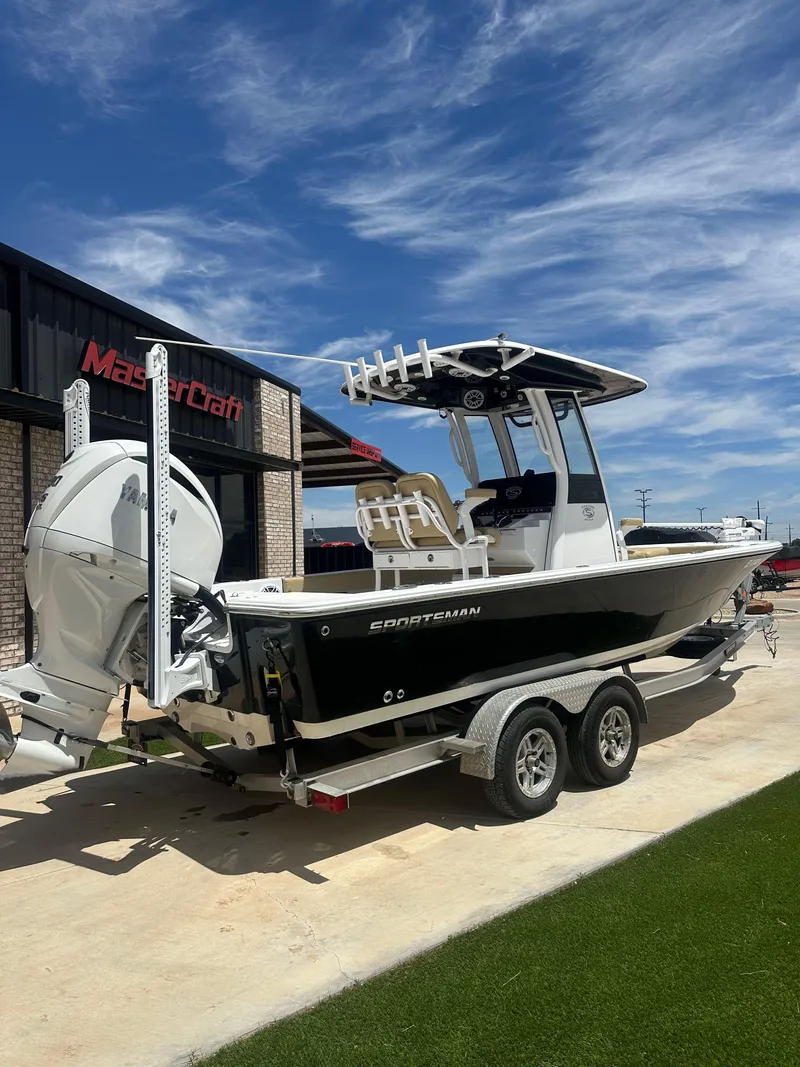 Slide: The Image of 2023 Sportsman Masters 247OE Bay Boat on trailer, parked outside dealership under blue sky. - 2