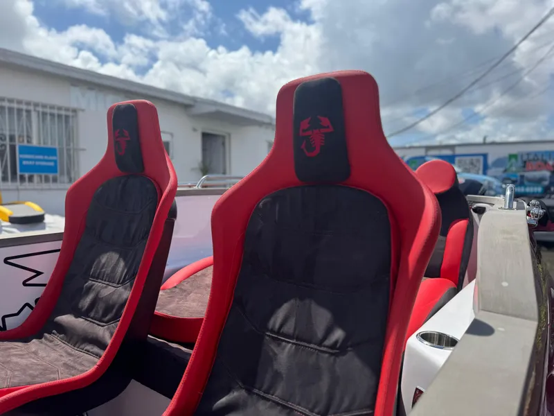 Slide: The Image of Red and black seats in a 2025 Car Off-shore Fiat 500 Abarth under a cloudy sky. - 6