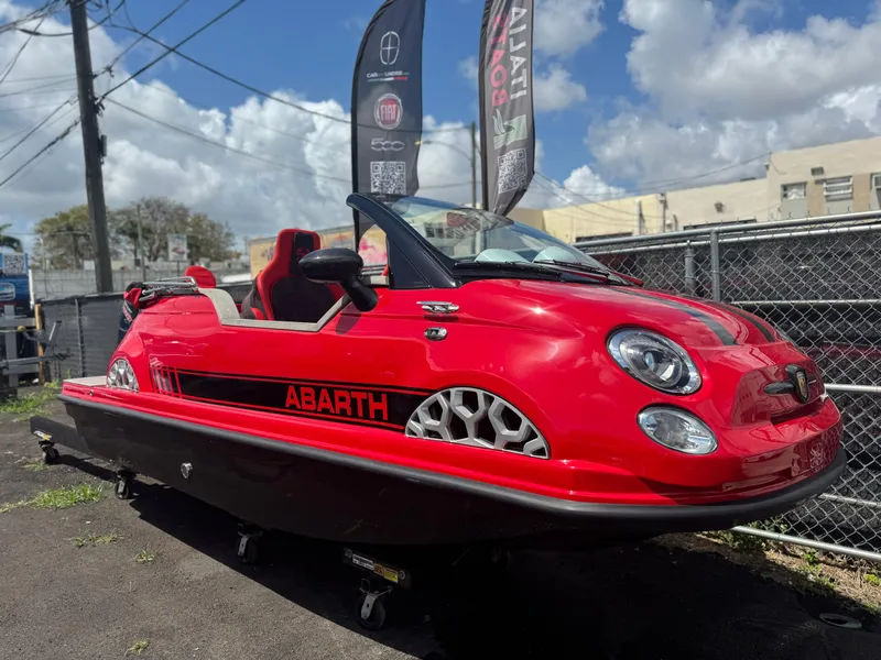 The Image of Red 2025 Fiat 500 Abarth boat hybrid, parked outdoors under a blue sky. - 0