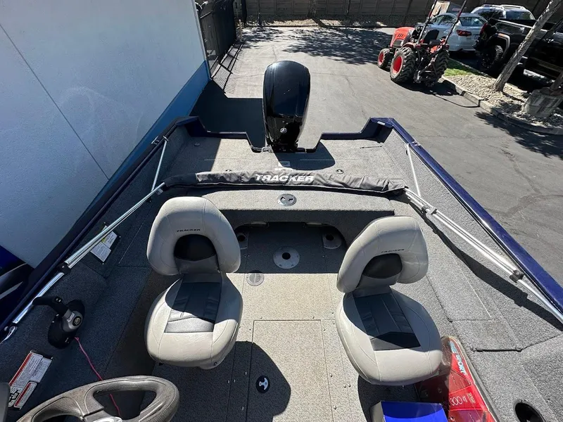 Slide: The Image of 2019 Tracker Pro Guide V-175 Combo boat interior with seating and motor, parked outdoors. - 11