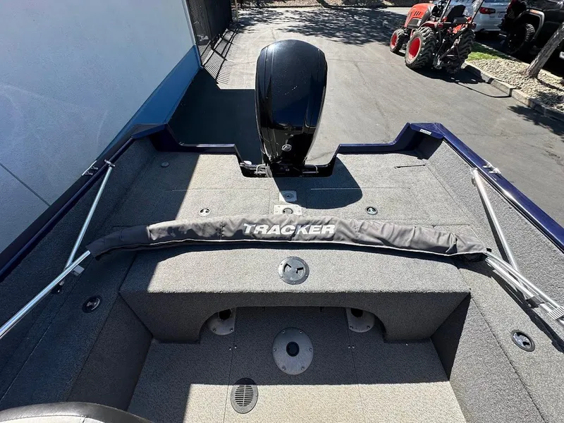 Slide: The Image of 2019 Tracker Pro Guide V-175 Combo boat interior with motor and cover, parked outdoors. - 13