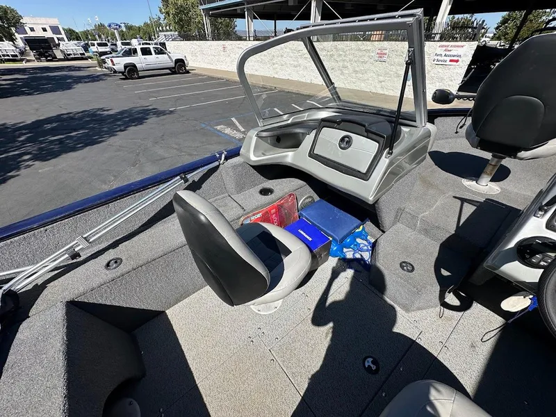 Slide: The Image of 2019 Tracker Pro Guide V-175 Combo boat interior with seating and dashboard in a parking lot. - 20