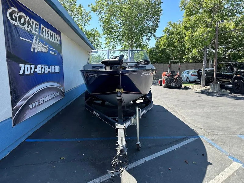 Slide: The Image of 2019 Tracker Pro Guide V-175 Combo boat on trailer at dealership, surrounded by trees and vehicles. - 3
