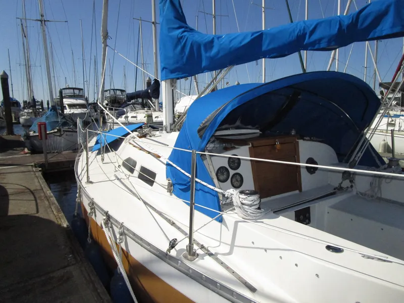 Slide: The Image of 1974 Irwin Competition 30 sailboat docked, featuring blue canopy and white hull. - 1