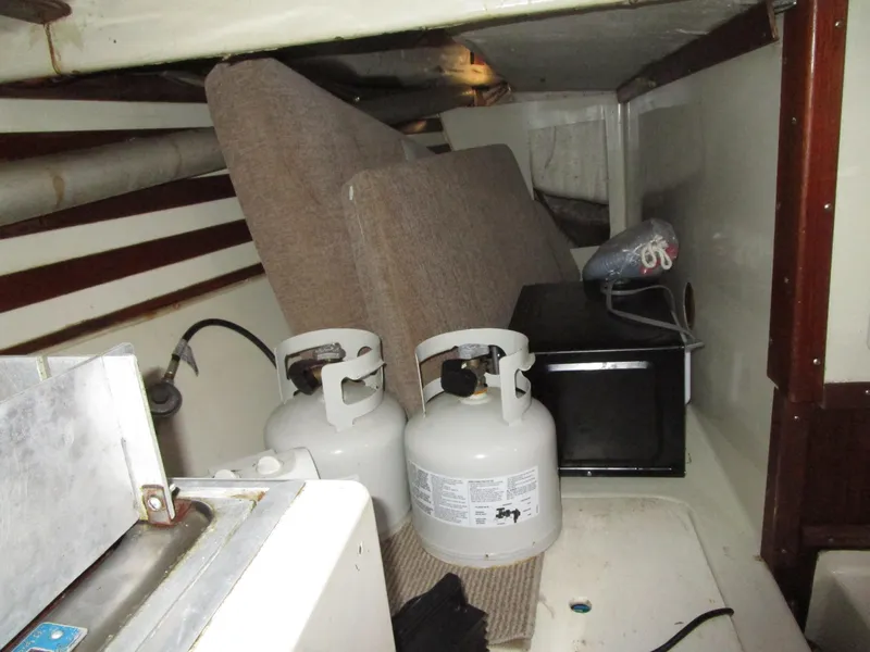 Slide: The Image of Interior of a 1974 Irwin Competition 30 sailboat with propane tanks and storage items. - 11